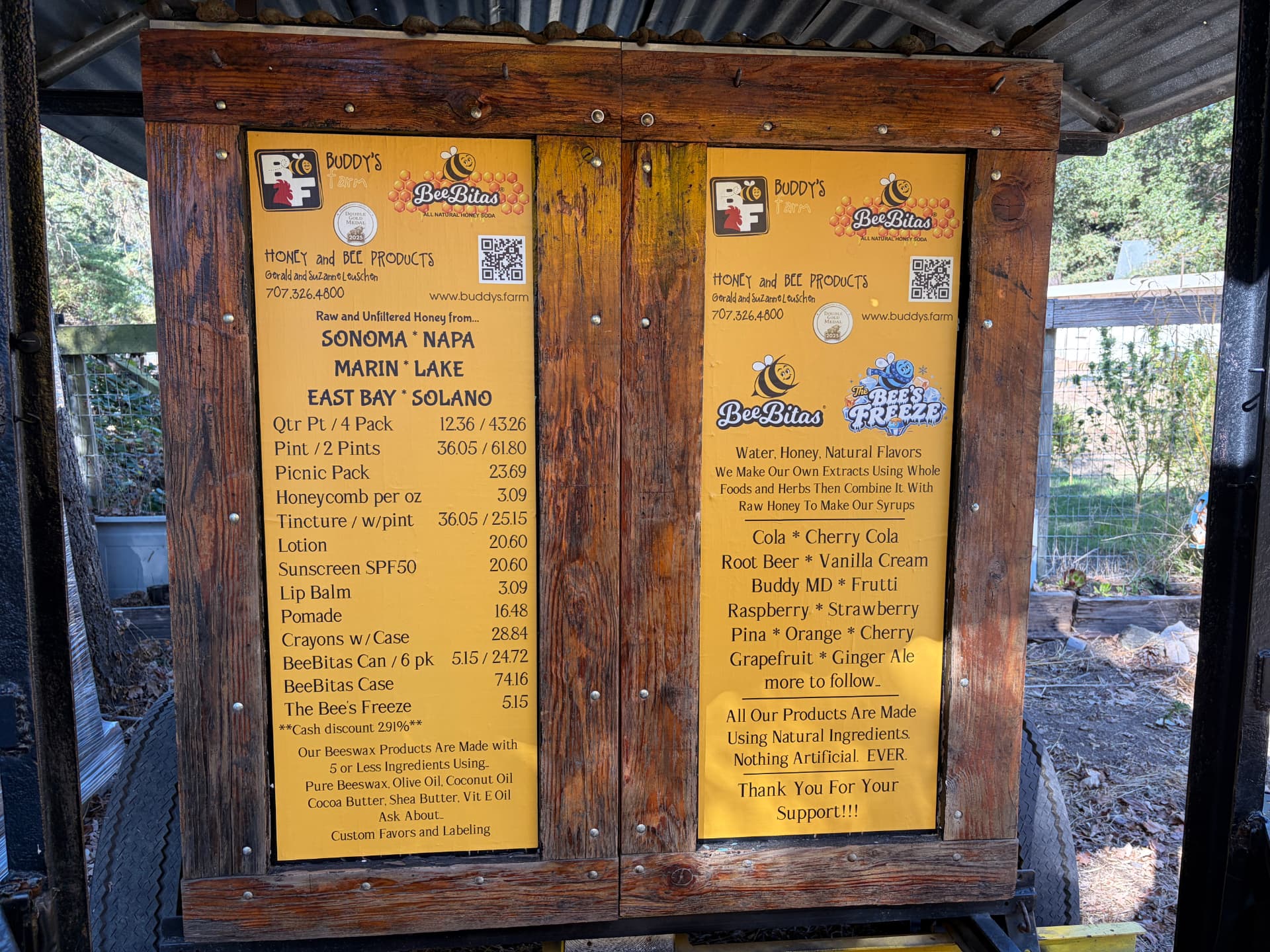 Hand-built wooden menu boards at the Buddy's Farm stand listing honey and BeeBitas flavors